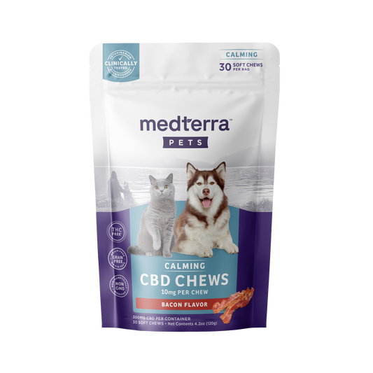 A package of Medterra Pet CBD Calming Chews with bacon flavor is displayed. The front showcases images of a gray cat and a brown and white dog. The package indicates that each chew contains 10mg, includes 30 soft chews, and highlights that it is clinically tested, THC-free, and enriched with Valerian Root for added relaxation.