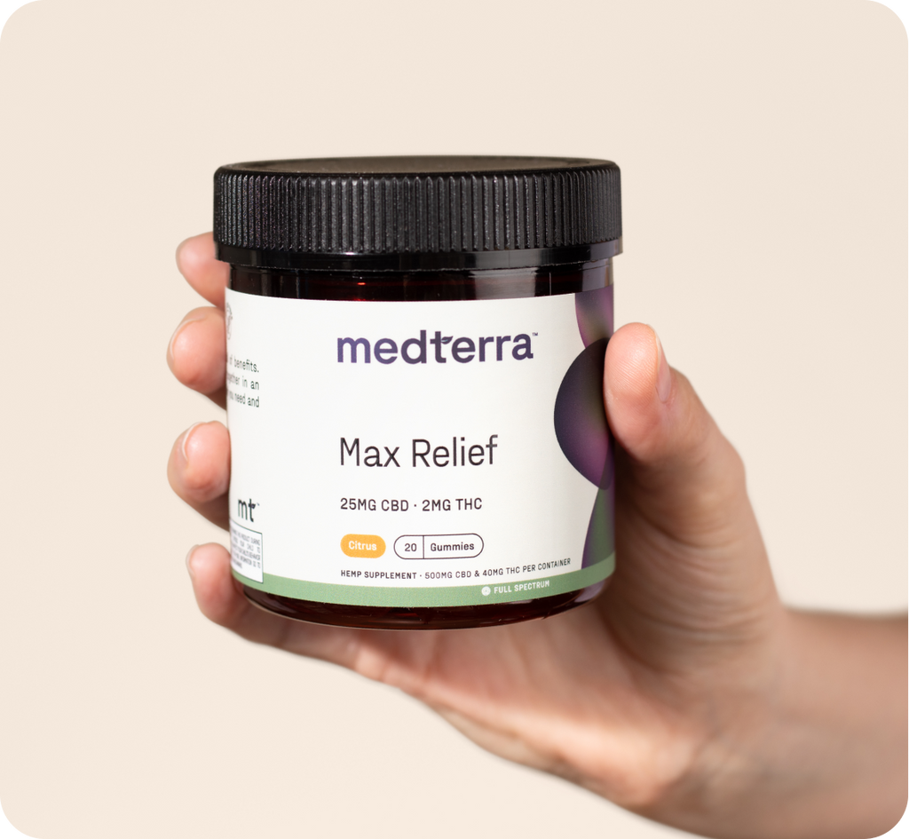 A hand holds a dark amber jar with a black lid labeled "medterra Max Relief, 25MG CBD - 2MG THC," containing 20 citrus-flavored gummies made from full spectrum hemp extract. The label mentions it's a dietary supplement and provides dosage instructions. The background is a plain neutral color.