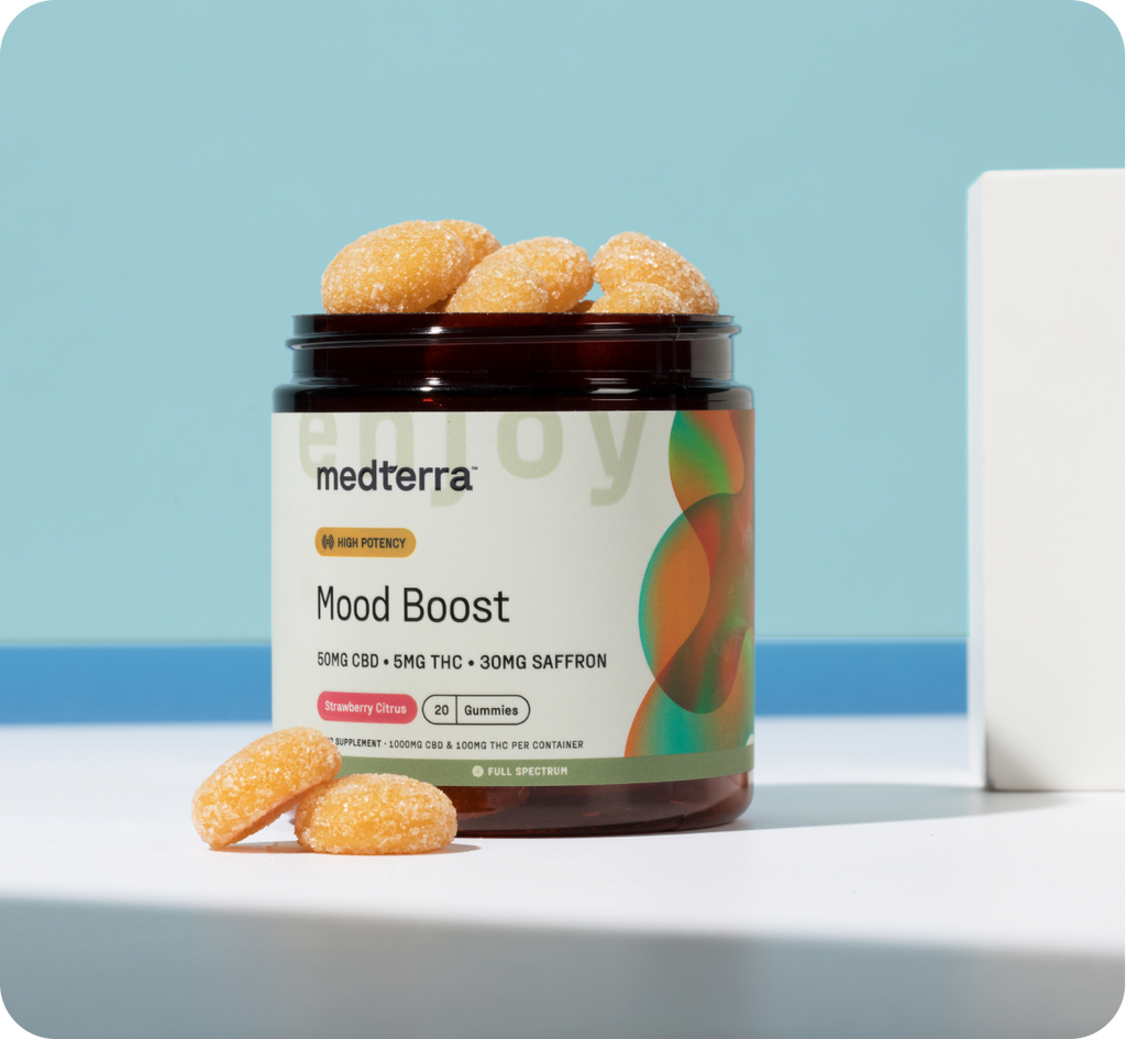 A jar of Medterra Mood Boost Gummies is shown with three gummies placed in front of it. The label on the jar reads "High Potency," boasting 50mg CBD, 5mg THC, and 30mg saffron per serving. The product is identified as "Strawberry Citrus" flavor and contains 30 gummies.